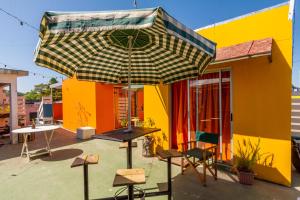a colorful house with a table and an umbrella at Del Barcito Hostel and Suites in Punta del Este