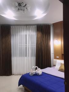 1 dormitorio con cama con sábanas azules y techo en Ok Farm Resort en Det Udom