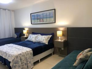 1 dormitorio con 1 cama azul y 2 lámparas en Apartamento Praia Grande, en Arraial do Cabo