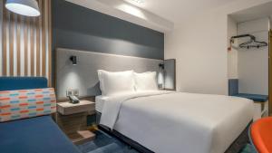 a bedroom with a white bed and a blue chair at Holiday Inn Express Qingdao City Center, an IHG Hotel in Qingdao