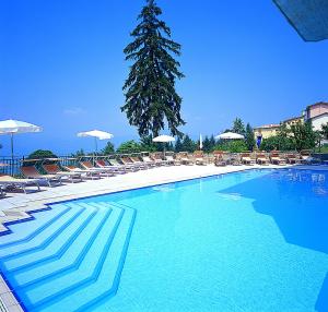 a large blue swimming pool with chairs and umbrellas at Albergo Sole in San Zeno di Montagna