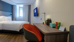 um quarto de hotel com uma cama e uma secretária com uma televisão em Holiday Inn Express Qingdao City Center, an IHG Hotel em Qingdao