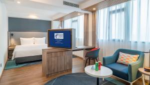 a hotel room with a bed and a tv at Holiday Inn Express Qingdao City Center by IHG in Qingdao