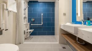 a bathroom with blue tiles and a sink and a toilet at Holiday Inn Express Qingdao City Center, an IHG Hotel in Qingdao