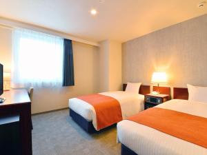 a hotel room with two beds and a window at FLEXSTAY INN Hakodate Station in Hakodate