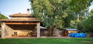 a stone house with a patio and a tree at El Vilarot. La casa de piedra en la naturaleza. in Girona