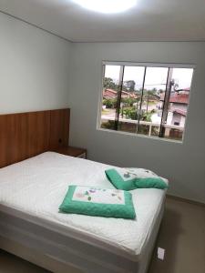 a bedroom with a bed with green towels on it at Apartamento encantador in Itapoa