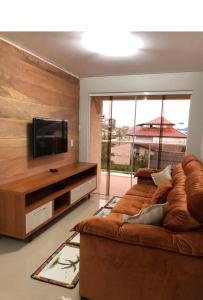 a living room with a brown couch and a flat screen tv at Apartamento encantador in Itapoa