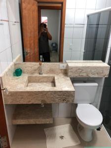 a person taking a picture of a bathroom sink at Apartamento encantador in Itapoa