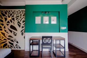 a dining room with two chairs and a green wall at Lá Hotel Bình Tân in Ho Chi Minh City