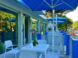 a table and chairs with blue umbrellas on a patio at Hotel Bermuda in Marina di Ravenna