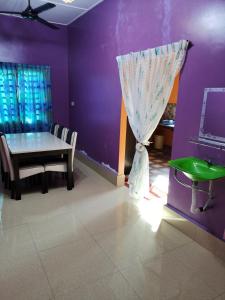 a dining room with a table and a purple wall at Homestay Che Wan Dua in Kuantan