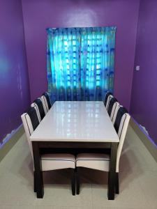 a dining room table with chairs and a blue curtain at Homestay Che Wan Dua in Kuantan
