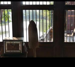 Ban Tha Pong的住宿－Rustic​ Charm​ Suphan​，坐在桌子旁窗户前的钟