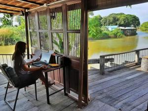 una mujer sentada en un escritorio con un portátil en Rustic​ Charm​ Suphan​, en Ban Tha Pong