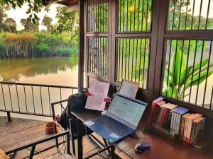 Ban Tha Pong的住宿－Rustic​ Charm​ Suphan​，坐在窗边的桌子上的笔记本电脑