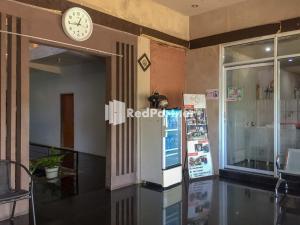 PalopoにあるWisma Andini Palopo RedPartnerの冷蔵庫のある部屋の壁に掛かっている時計