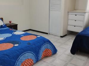 a bedroom with a bed with a blue comforter at CASA HOTEL MODELIA REAL in Bogotá