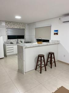 a kitchen with a counter and two bar stools at FÉRIAS EM FLORIPA, ILHA DA MAGIA! in Florianópolis