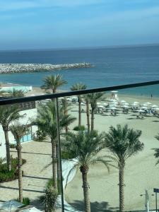 uma vista para uma praia com palmeiras e para o oceano em luxury sea view Address Hotel apartment Fujairah em Fujairah