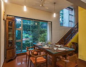 une salle à manger avec une table, des chaises et une grande fenêtre dans l'établissement SaffronStays Aurelia, Panchgani - Balinese villa with breathtaking valley views, à Panchgani