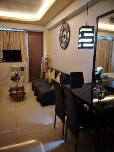 een woonkamer met een bank, een tafel en een klok bij One Palm Tree Villas NAIA TERMINAL 3 in Manilla