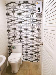 a white bathroom with a toilet and a sink at Baan PhakDeeChan in Chanthaburi