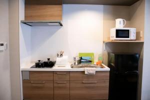 una pequeña cocina con fregadero y microondas en Hotel S-Presso West en Osaka