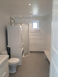 a white bathroom with a toilet and a shower at Timmerstugan in Borlänge