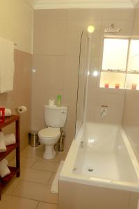 a white bathroom with a tub and a toilet at Hotel @ Tzaneen in Tzaneen