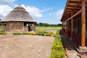a building with a thatch roof and a garden at MARK's farm & ecolodge in Kalenga