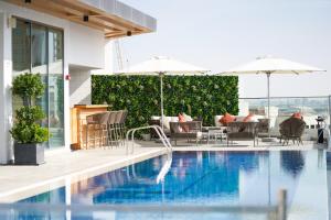 - une piscine avec des chaises et des parasols dans un bâtiment dans l'établissement IntercityHotel Dubai Jaddaf Waterfront, à Dubaï