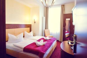 a hotel room with a bed with two towels on it at Hotel Arena City in Leipzig