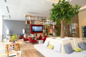 a living room with a tree on a white couch at IntercityHotel Dubai Jaddaf Waterfront in Dubai