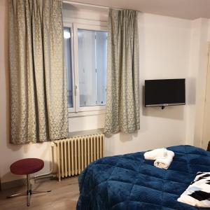 a bedroom with a blue bed and a window at Hotel Restaurant Les Oceanides in Concarneau