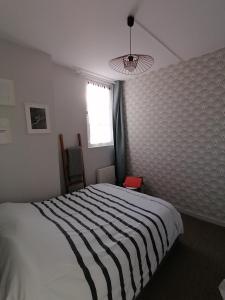 een slaapkamer met een zwart-wit bed en een raam bij A la "Georgette" et son jardin avec parking in Villers-sur-Mer