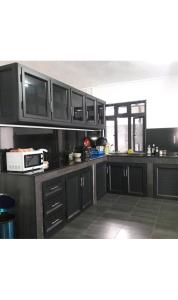 a kitchen with black cabinets and a microwave at Sunrise Sensation holiday home. in Centre de Flacq