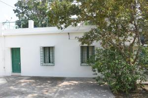 um edifício branco com uma porta verde em Bhitey Homestay SIMANTAPALLY / SHANTINIKETAN em Santiniketan