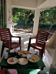 una mesa con platos de comida en ella con dos sillas en Bhitey Homestay SIMANTAPALLY / SHANTINIKETAN, en Santiniketan