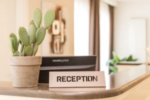 een plant op een tafel met een bord dat de ontvangst leest bij Hotel & Residence Exclusive in Marina di Carrara