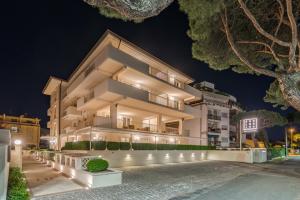 un grande edificio bianco di notte con luci di Hotel & Residence Exclusive a Marina di Carrara