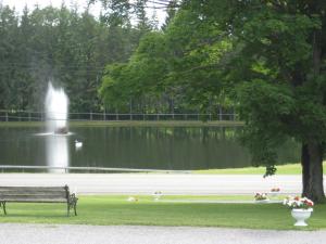 un banco de parque frente a un estanque con una fuente en Fountain View Motel, en Richfield Springs