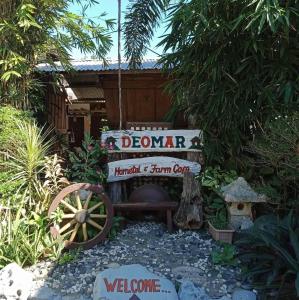 un cartel de bienvenida y una rueda de agua en un jardín en RedDoorz Hostel @ Deomar Hometel & Farm Cafe Ilocos Sur, en Bantaoay