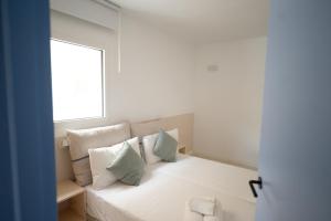 a bedroom with a bed with pillows and a window at JUST EXPERIENCE MALLORCA in Andratx