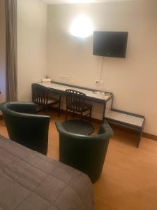 a room with a table and chairs and a television at hôtel du commerce in Joncy