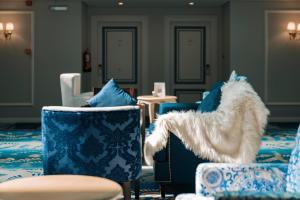 a living room with blue and white chairs at Gulanar Hotel in Unayzah