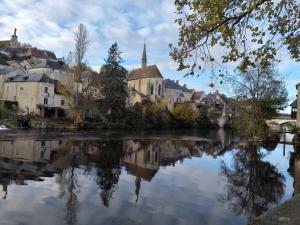 a view of a river with buildings and a church at Maison Berrichonne 2 chambres cour et jardin in Saint-Marcel