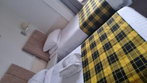 a bed with a yellow and black checkered blanket at Hampton Court Guesthouse - City Centre in Glasgow