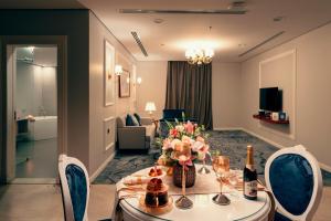 ウナイザにあるGulanar Hotelの花とワインのボトルを用意したテーブルが備わる客室です。