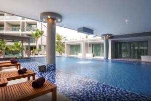 a swimming pool with two benches in a building at laguna regent condo by AM in Phuket Town